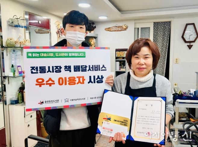 대송시장 헤어세상 심영미 사장이 동부도서관이 주관한 '전통시장 책 배달 프로그램' 우수이용자상을 받고 기념사진을 찍고있다